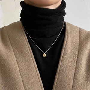 Detail of gold necklace with irregular textured molten pendant on a black turtleneck
