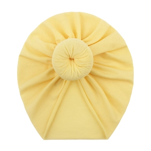 Soft yellow cotton donut knot hat for infants with stretchy fabric on white background