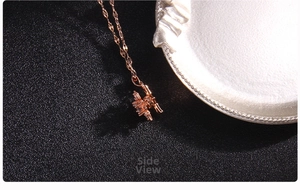 Macro side view of rose gold clover pendant with cubic zirconia inlay on black base