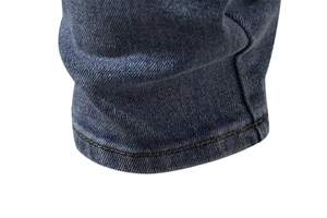 Macro detail of classic blue jeans showing high-quality double-stitched hem and twill texture