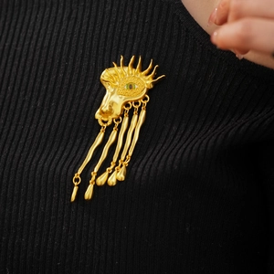 Detailed shot of a vintage gold eye brooch with crystal rhinestones and five teardrop charms
