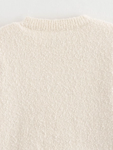 Close-up of cream bouclé knit texture and round neckline of a soft sweater