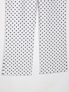 Vue détaillée du tissu blanc à pois noirs et de l'ourlet piqué du pantalon évasé