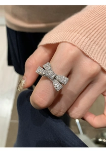 Close-up of a silver-toned bow ring with sparkling zircons worn on a finger