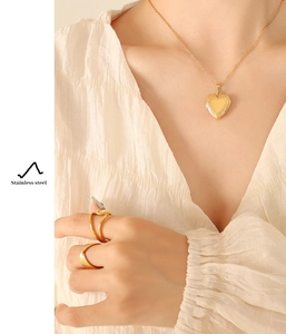 Close-up of 18K gold plated stainless steel heart locket necklace and rings set on model