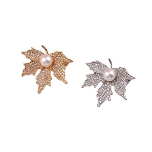 Detailed view of maple leaf brooches with pavé zircon stones and white pearls in gold and silver