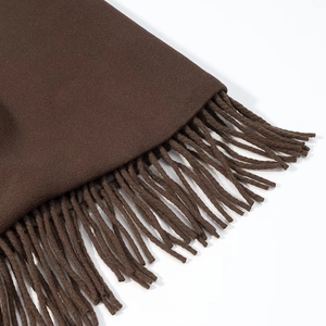 Gros plan sur la texture en laine marron et les franges du long manteau à la mode