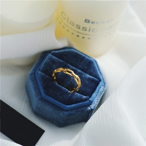 Vue détaillée d'une bague chaîne dorée dans un écrin hexagonal en velours bleu