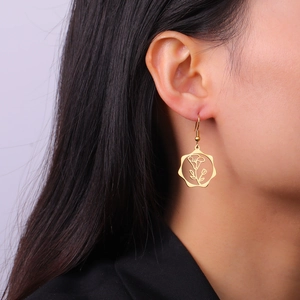 Close-up of a model wearing a gold floral hollow-out hexagon pendant earring