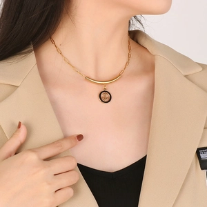 Detail of golden titanium steel heart necklace with anchor pendant on a female model