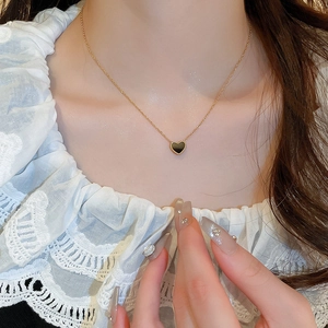 Collier minimaliste à double face avec cœur noir en finition dorée porté par un mannequin