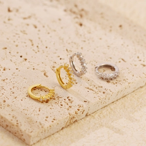 Macro shot of gold and silver huggie earrings with cubic zirconia on stone base
