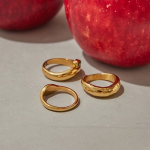 Detailed view of three-piece gold-plated zircon ring set on a modern textured background
