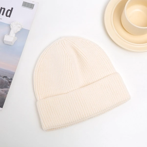 Detailed texture of thick cream knitted beanie hat with fold-over cuff for winter
