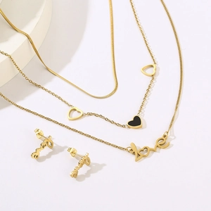 Detailed macro of gold layered necklace set with heart charms and love letter pendants