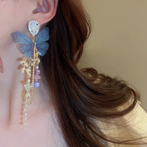 Detailed close-up of long blue mesh butterfly tassel earrings worn by a model