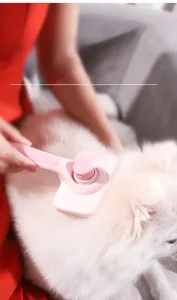 Pink pet grooming brush with ergonomic handle removing fur from a white long-haired dog