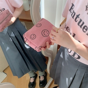 Detail of pink corduroy makeup bag with black smiley print and zipper closure