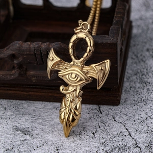 Macro shot of gold Eye of Horus Ankh cross pendant resting on a dark wood box