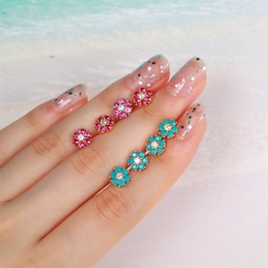 Mini flower stud earring set with zircons in pink and blue colors on hand display