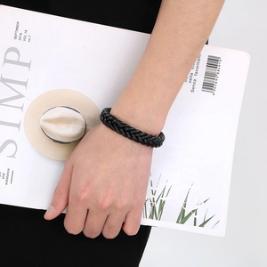 Detail of a braided black leather steel bracelet on a wrist with a minimalist look
