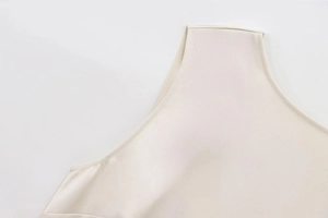 Close-up of neckline sewing details and fabric texture on a beige sleeveless dress