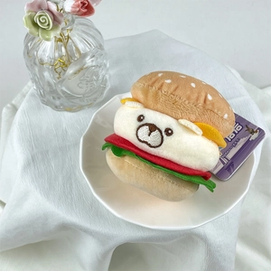 Detail of cute plush burger keychain with white bear filling on white fabric background