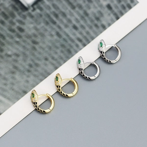 Detail of snake hoop earrings with green zircon eyes and black patterned texture