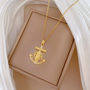 Close-up of golden anchor and portrait pendant with crystals in a luxury jewelry box