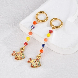 Detailed close-up of bohemian earrings with colorful beads and fish charm on stone