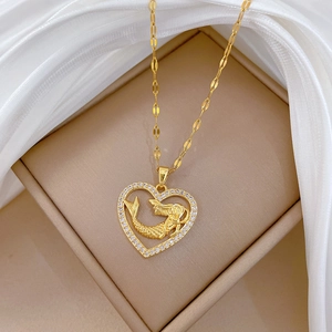 Detail of gold heart pendant with mermaid motif and diamonds on white silk fabric