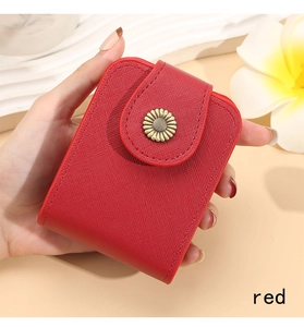 Detail of red cross-grain leather makeup bag with daisy metal buckle held by hand