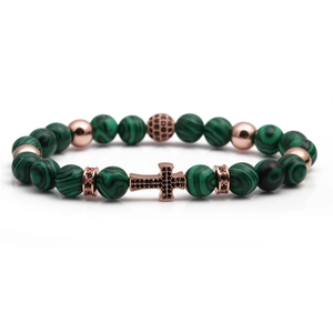 Macro shot of malachite beaded bracelet with rose gold charms and black cross pendant