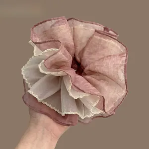 Macro detail of large layered pink chiffon hair scrunchie with cream lace trim edges