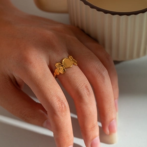 Detail of gold-plated titanium steel ring with clover charms and polished round disc