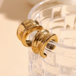 Vue macro de boucles d'oreilles clips bombées en acier doré 18 carats sur un verre