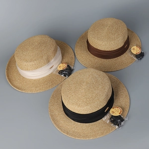 Vue détaillée de chapeaux canotiers tressés en beige avec rubans plissés marron et noir