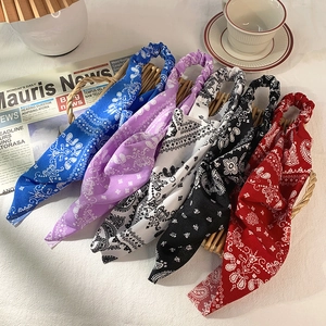 Set of five paisley printed elastic headbands in assorted colors displayed on a woven basket