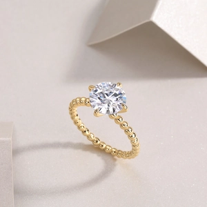 Detail of gold plated S925 silver moissanite ring with beaded band and 4-prong setting