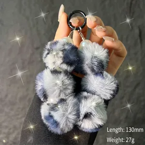 Detail view of multi-color plush pompom keychain with pearls and black clip 130mm long