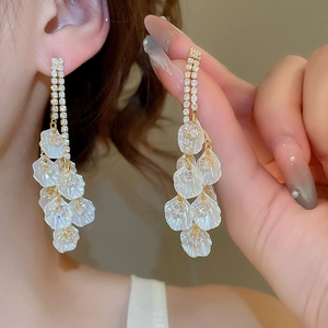 Gros plan sur des boucles d'oreilles dorées avec pétales blancs et pierres de cristal
