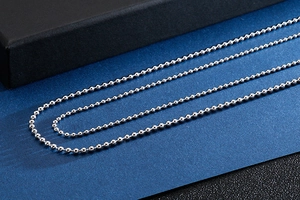Polished stainless steel bead chain necklace displayed on a dark textured background