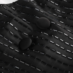 Gros plan sur un tissu noir à paillettes avec perles rectangulaires et boutons