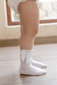Close-up of girls white cotton socks with large bow and wave lace edge detailing