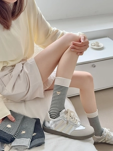 Detail of striped cotton crew socks featuring cute yellow bear embroidery in a soft aesthetic