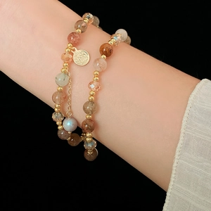 Close-up of multi-layer beaded bracelet with crystal stones and gold coin charm