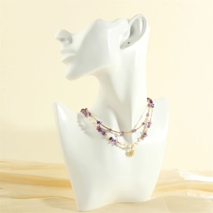 Close-up of double-layer necklace with purple gravel, white pearls and gold sun pendant