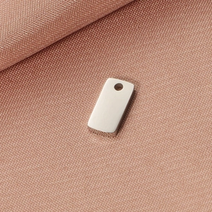 Macro detail of polished silver rectangular stainless steel tag with small hole for DIY jewelry