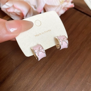 Dettaglio degli orecchini a fiocco in smalto rosa su cartoncino per accessori