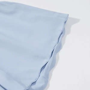 Close-up of light blue fabric texture and decorative wavy edge stitching detail